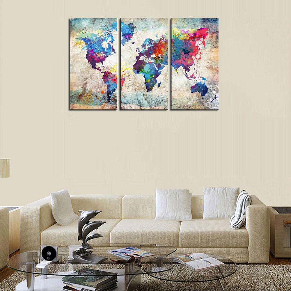 World Map in Paint Spatter - Three panel canvas wall art featuring vibrant watercolor-style world map with colorful paint splatters on beige background, displayed above modern living room sofa
