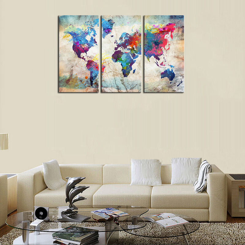 World Map in Paint Spatter - Three panel canvas wall art featuring vibrant watercolor-style world map with colorful paint splatters on beige background, displayed above modern living room sofa