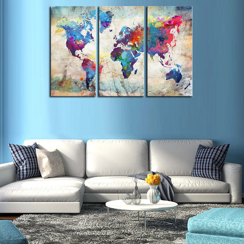 World Map in Paint Spatter: Vibrant 3-panel canvas art featuring a world map rendered in colorful paint splatters and watercolor effects against a vintage-style beige background, mounted above a modern living room sofa