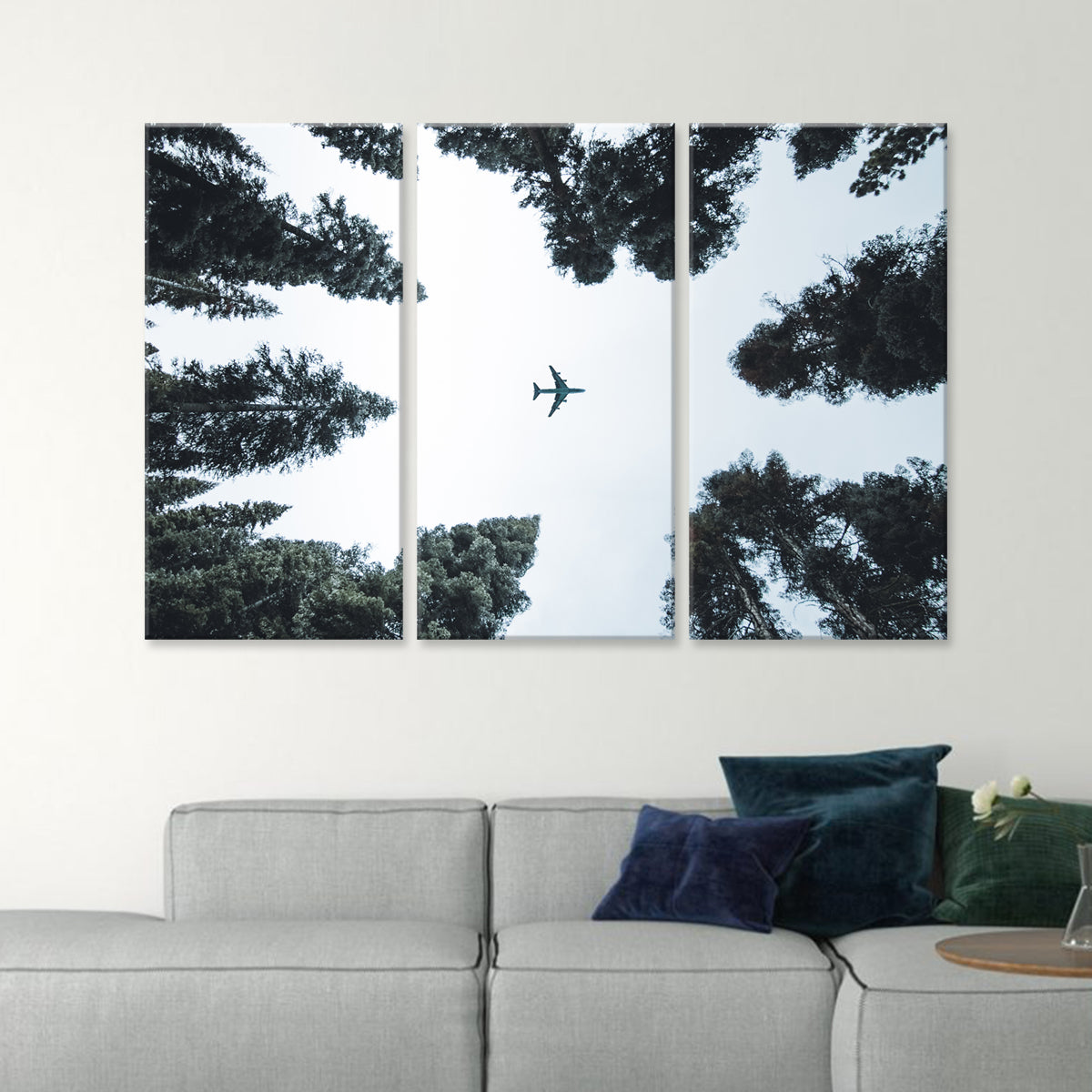 Airplane Above the Forest - 3-panel canvas wall art featuring silhouette of plane flying through white sky, framed by towering evergreen trees viewed from below, creating dramatic perspective and peaceful nature scene.