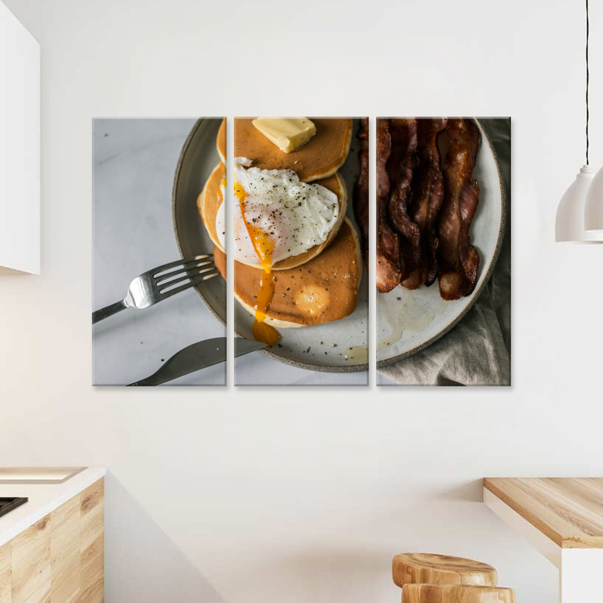 Bacon & Eggs - Three-panel canvas wall art featuring a close-up of a breakfast plate with crispy bacon strips, sunny-side-up egg with runny yolk, and black pepper, displayed in a modern kitchen setting with white walls