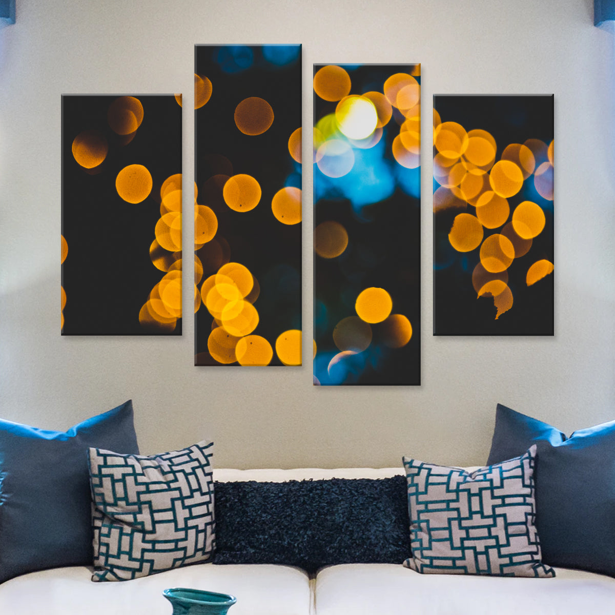 Ambient Lights canvas print featuring abstract bokeh effect with glowing orange circles and blue accents, displayed as a 4-panel wall art above modern blue and white patterned throw pillows on a couch