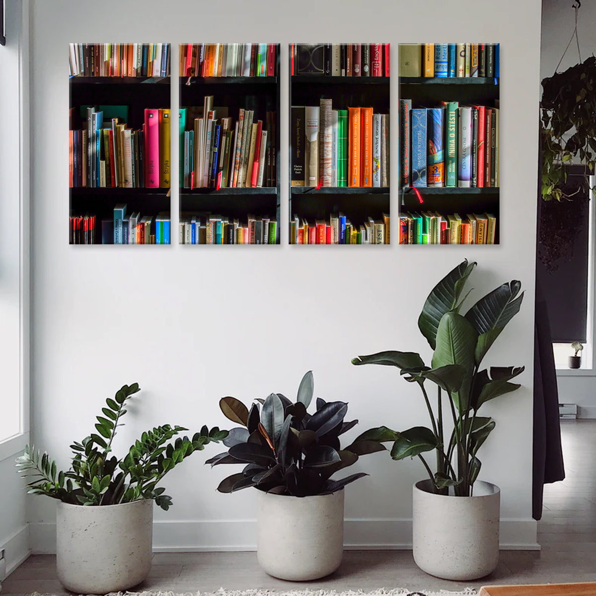Book Shelf canvas print featuring vibrant multicolored books arranged on dark shelves in a 4-panel wall art display, positioned above three potted tropical plants in modern gray planters against a white wall