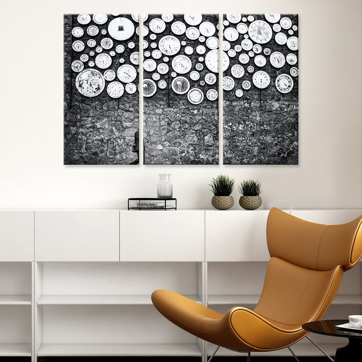 Wall of Clocks: Black and white three-panel canvas art featuring vintage clocks in various sizes floating against a textured stone background, creating a modern artistic timepiece display above white furniture and tan leather chair.