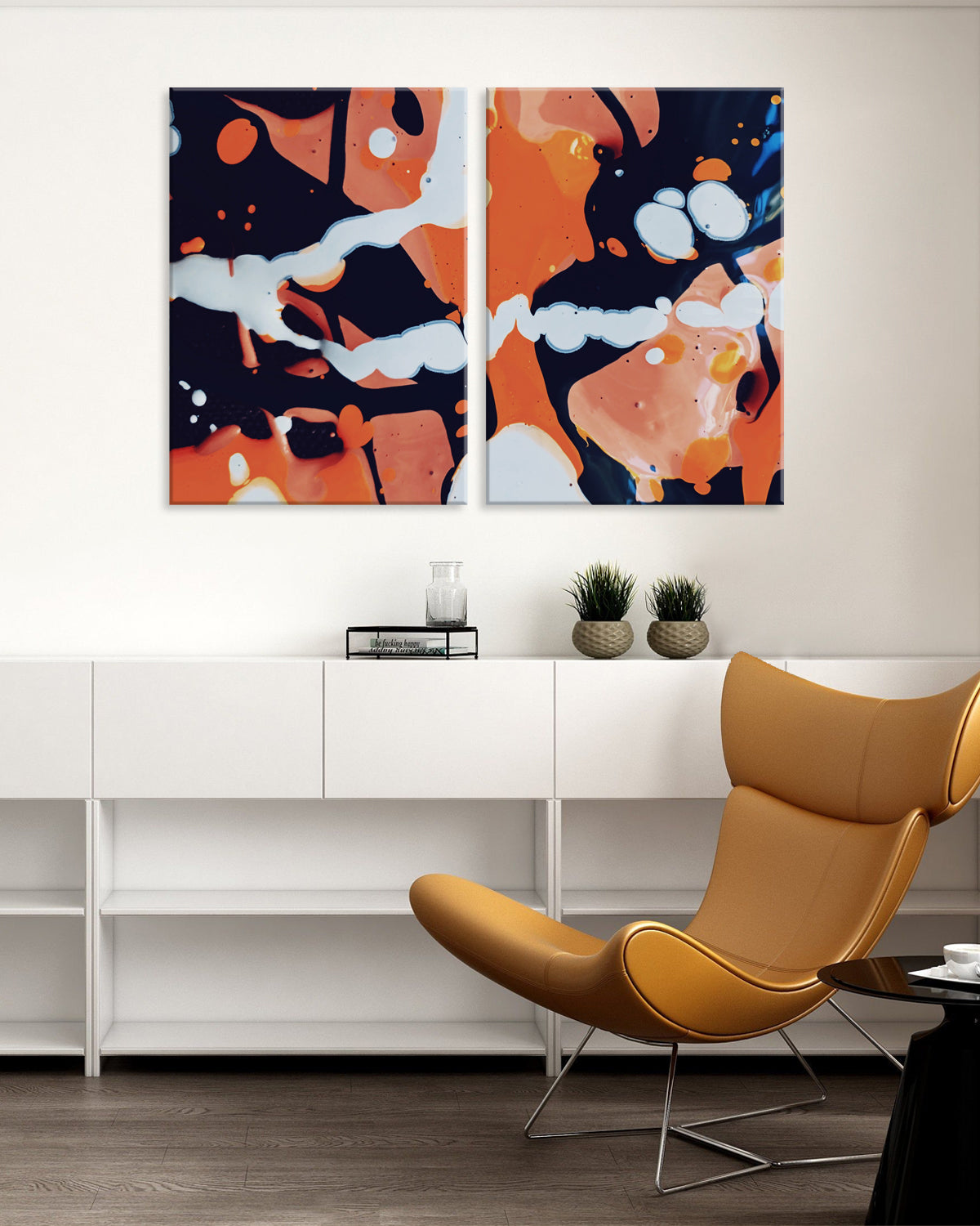 Colourful Paint Drips - Modern abstract canvas art featuring vibrant orange and white paint splatters on dark background, split into two panels, displayed above white cabinet with modern tan leather chair