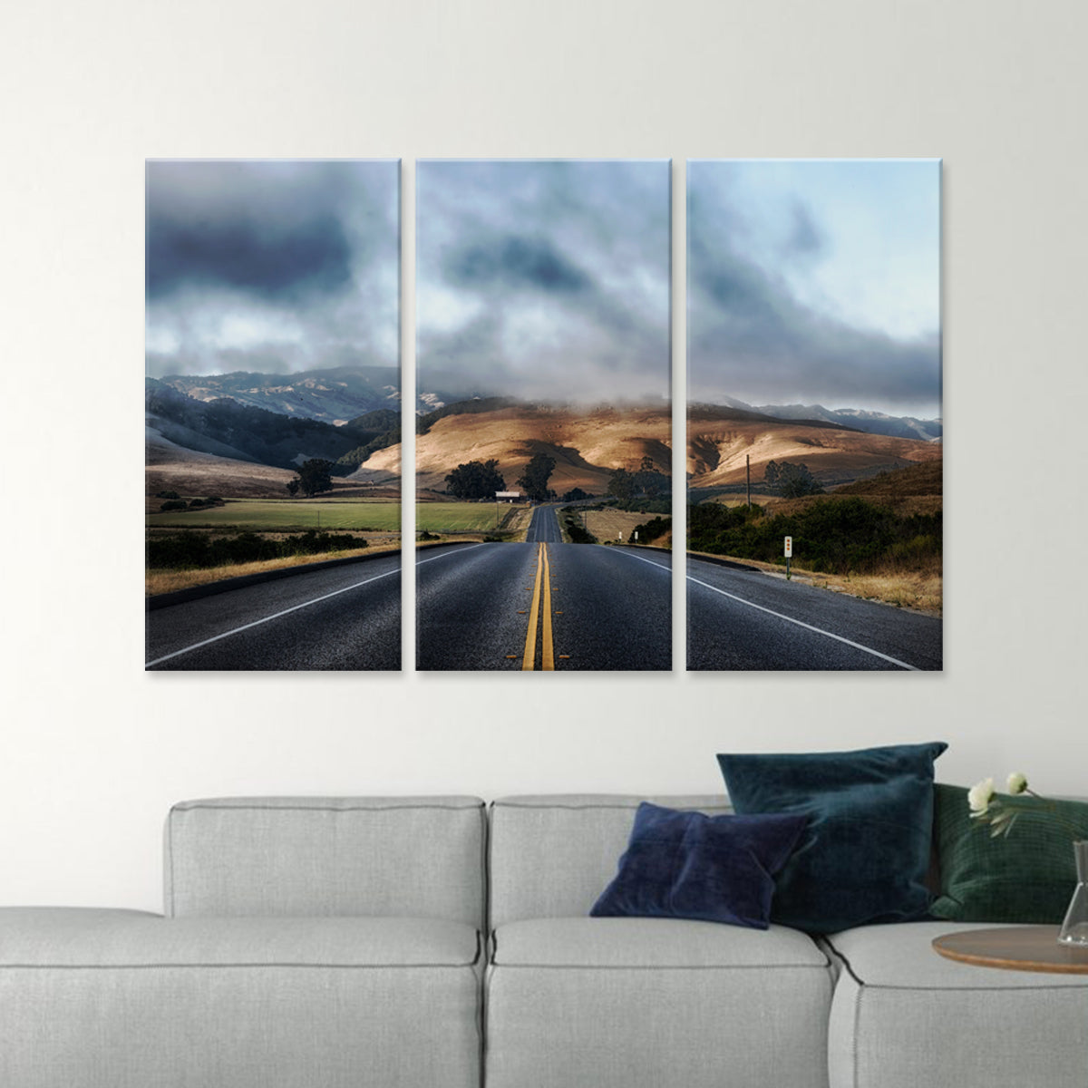 Open Road canvas print: Dramatic three-panel wall art featuring a winding highway through rolling hills, with stormy clouds and mountains in the distance, perfect for home decor and adventure enthusiasts