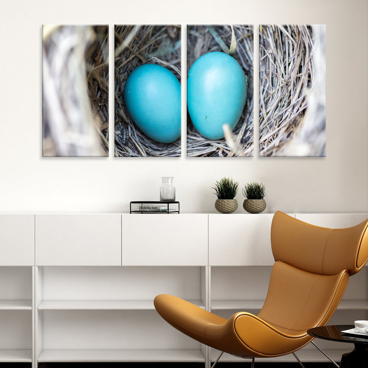 Robin Eggs in Nest - Four-panel canvas wall art showing bright turquoise robin eggs nestled in a natural grey twigs nest, displayed above white modern furniture in a contemporary home setting