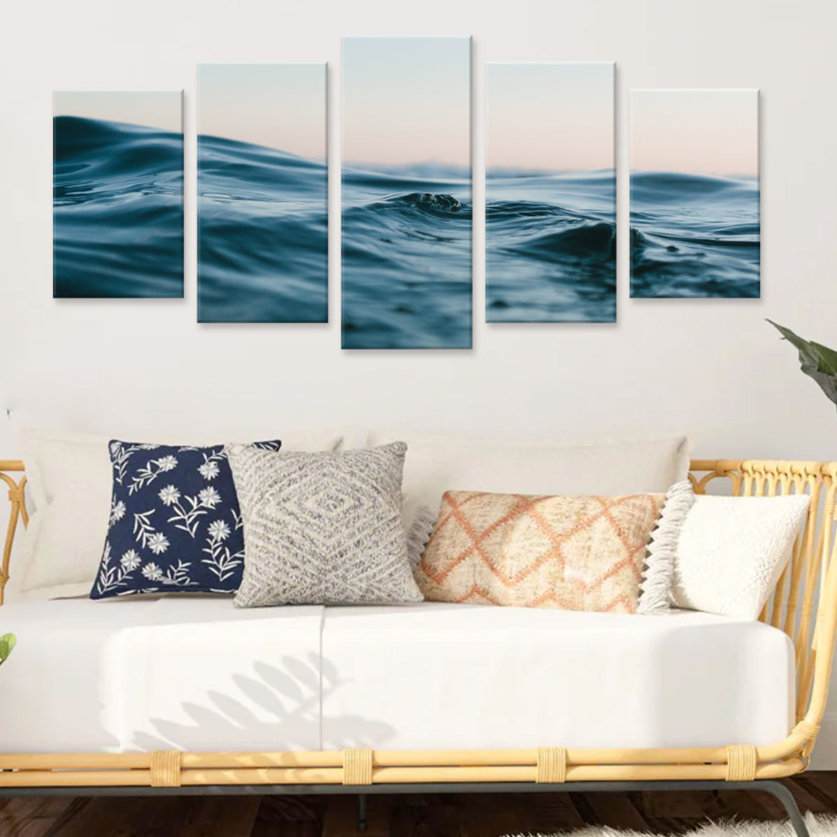 Water - 5 panel canvas wall art featuring serene ocean waves in deep teal blue against a soft pink sunset sky, displayed above white modern couch with decorative pillows