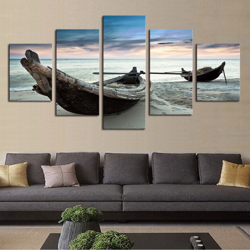 Canoes on the Beach: Two weathered wooden fishing boats resting on a serene sandy beach at sunset, with tranquil ocean waters and soft clouds in a blue-gray sky creating a peaceful coastal scene