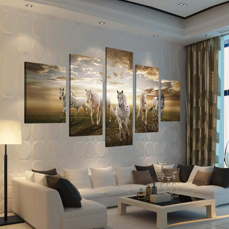 Beautiful Running Horses - 5-panel canvas wall art displaying white horses galloping across a meadow at sunset, dramatic golden sky backdrop, mounted in modern living room with white sectional sofa