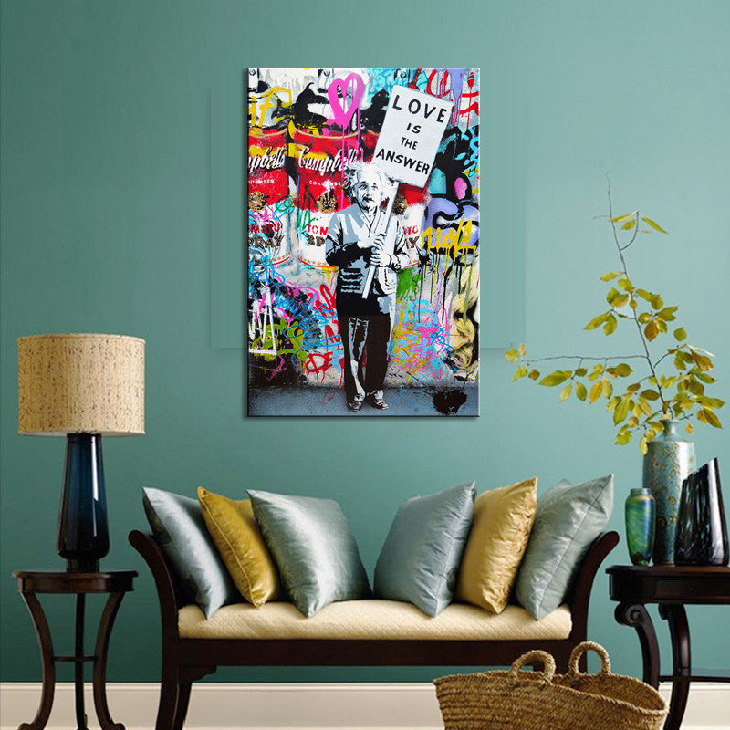 Love Is The Answer Banksy canvas print showing a figure in black silhouette holding a sign against vibrant graffiti-covered wall, displayed in modern living room with teal walls and cream sofa