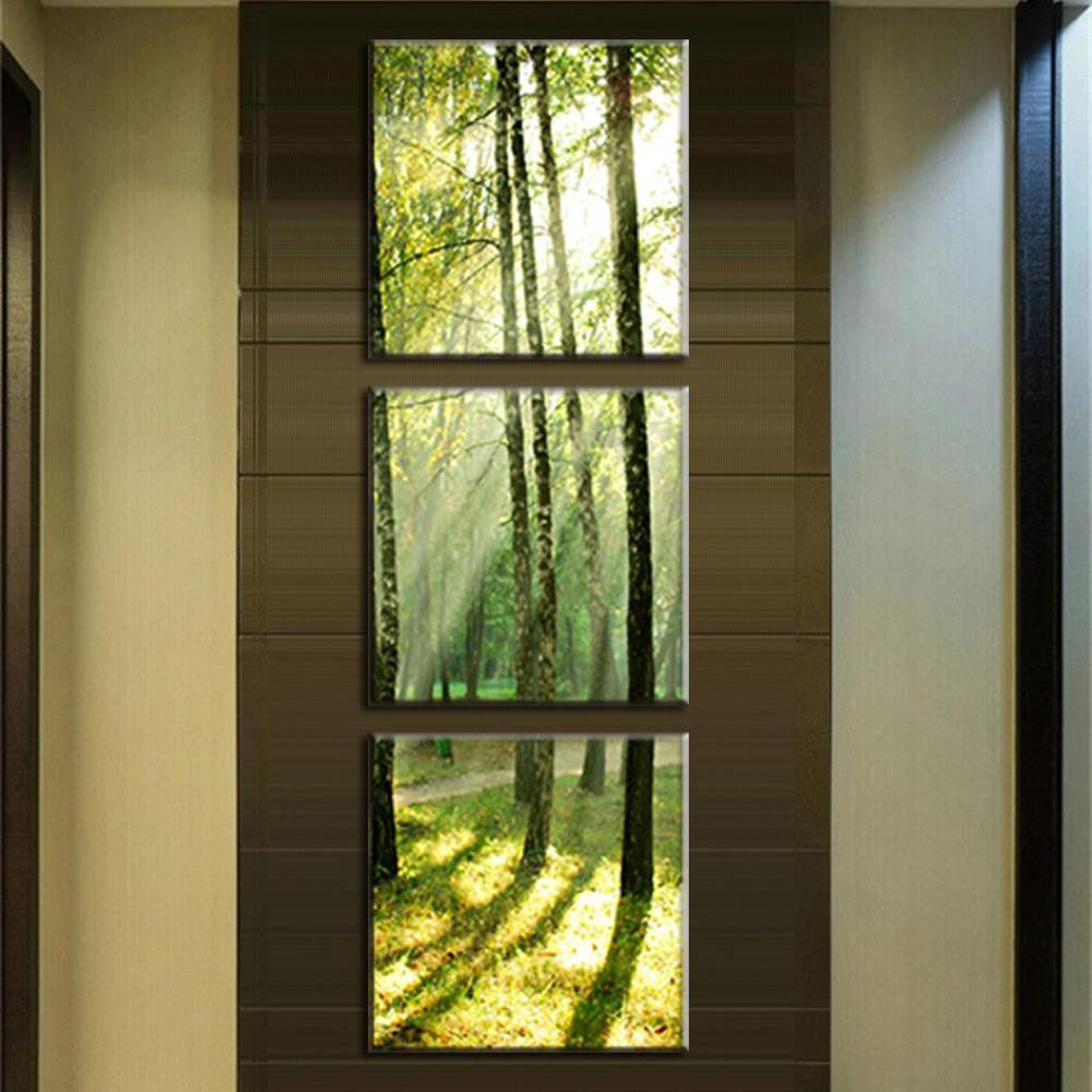 Sunshine Through the Trees - Vertical triptych canvas wall art featuring sunlit forest scene with golden rays filtering through green trees, creating dramatic shadows on forest floor, displayed on dark accent wall