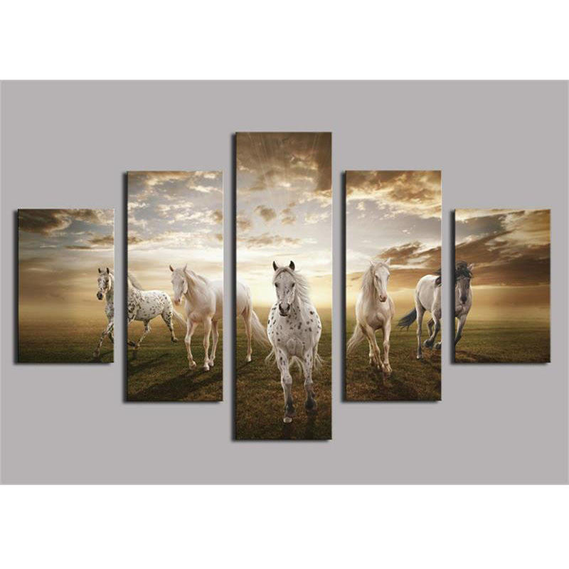 Beautiful Running Horses - Five white horses galloping across a grassy field at sunset with dramatic golden clouds overhead, split into a 5-panel canvas wall art set measuring 60 x 32 inches total