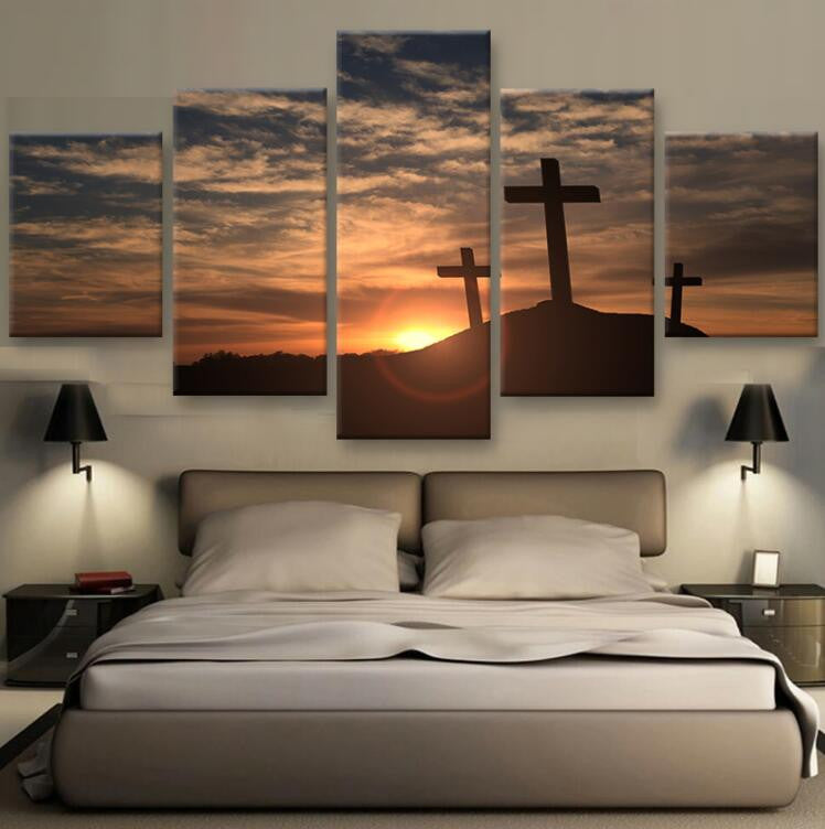 Crosses in the Sunset - Dramatic 5-panel canvas wall art featuring silhouetted crosses against a golden sunset sky with dramatic clouds, mounted above bed with wall sconces, creating a peaceful bedroom atmosphere
