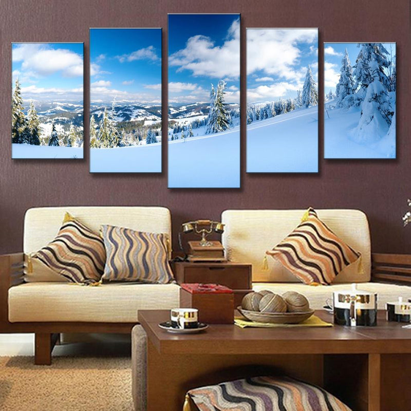 Winter Mountain Landscape: Snow-covered evergreen trees dot a pristine mountainside under bright blue sky with white clouds, panoramic view of rolling snowy hills and distant mountain peaks creating a serene winter wonderland scene