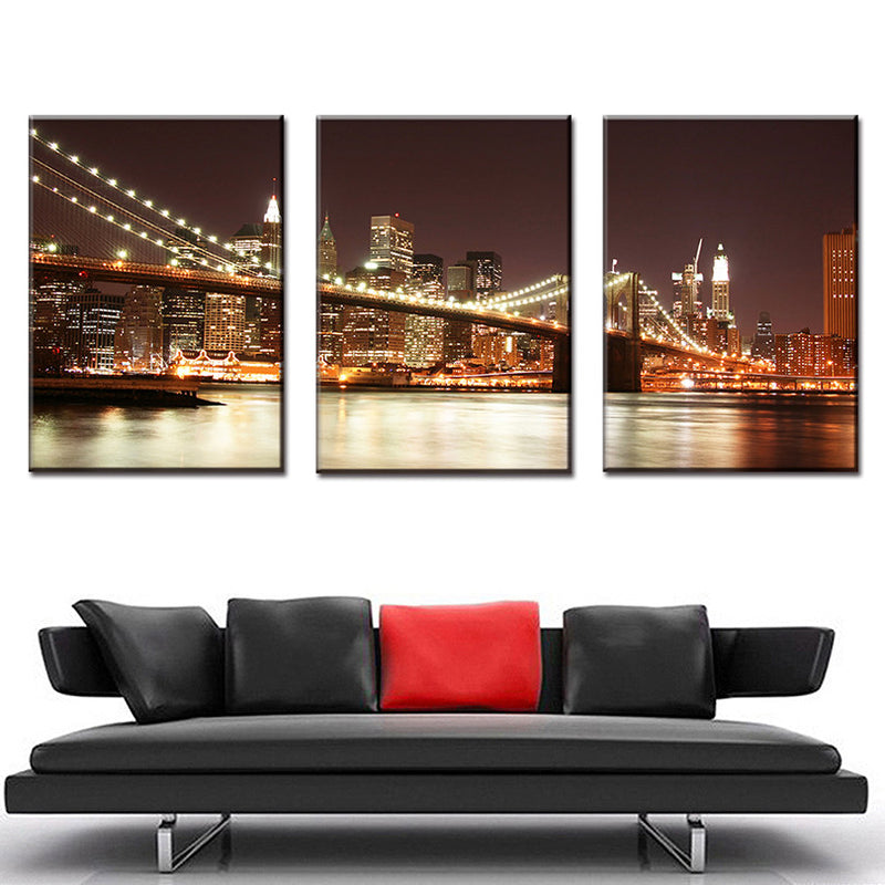 The Brooklyn Bridge at Night - Stunning 3-panel canvas wall art featuring illuminated Brooklyn Bridge with glowing city lights reflecting on East River, Manhattan skyline backdrop in warm sepia tones