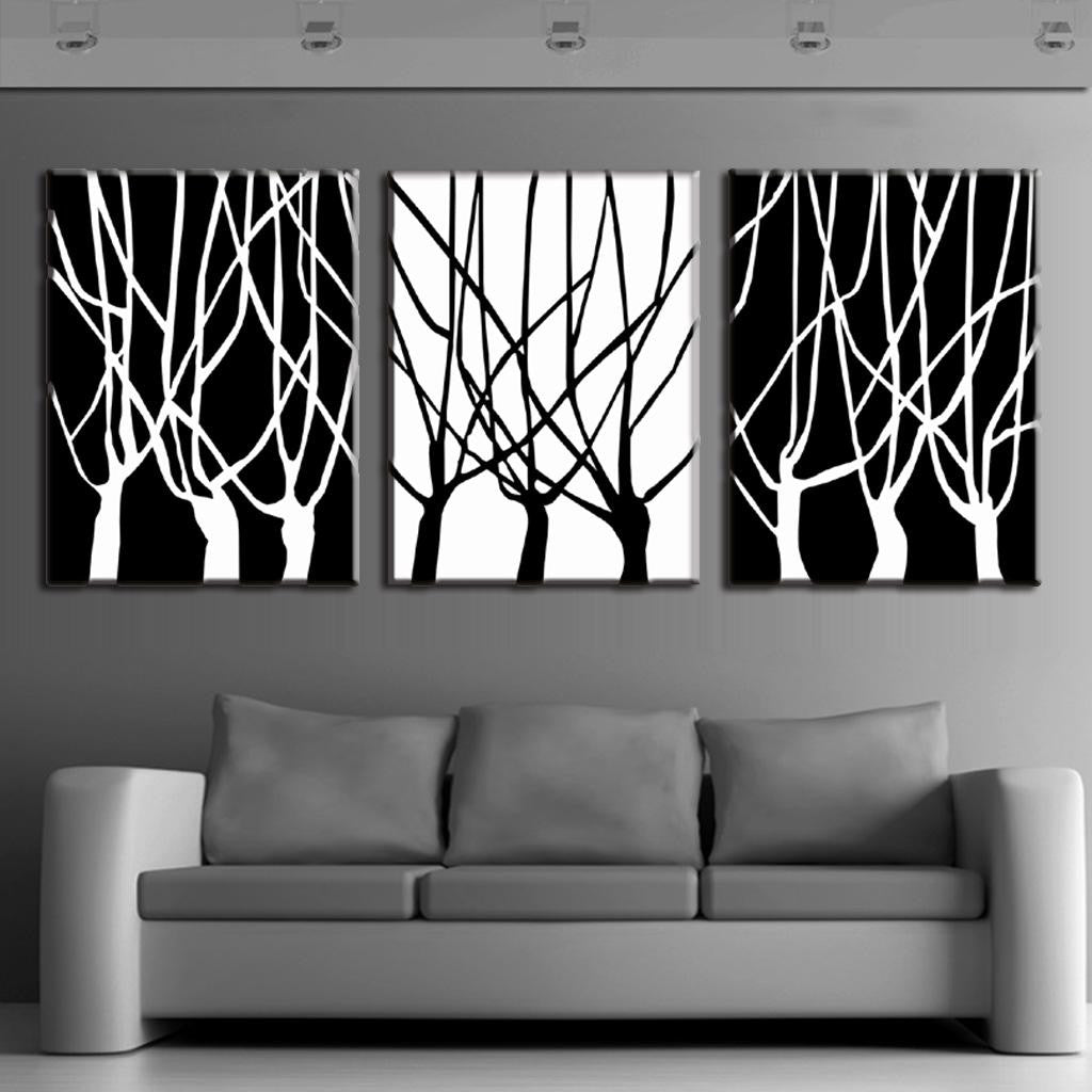 Black and White Tree Silhouettes: Three-panel modern canvas wall art featuring contrasting black and white minimalist tree branch silhouettes, displayed above a gray sofa in a contemporary room setting