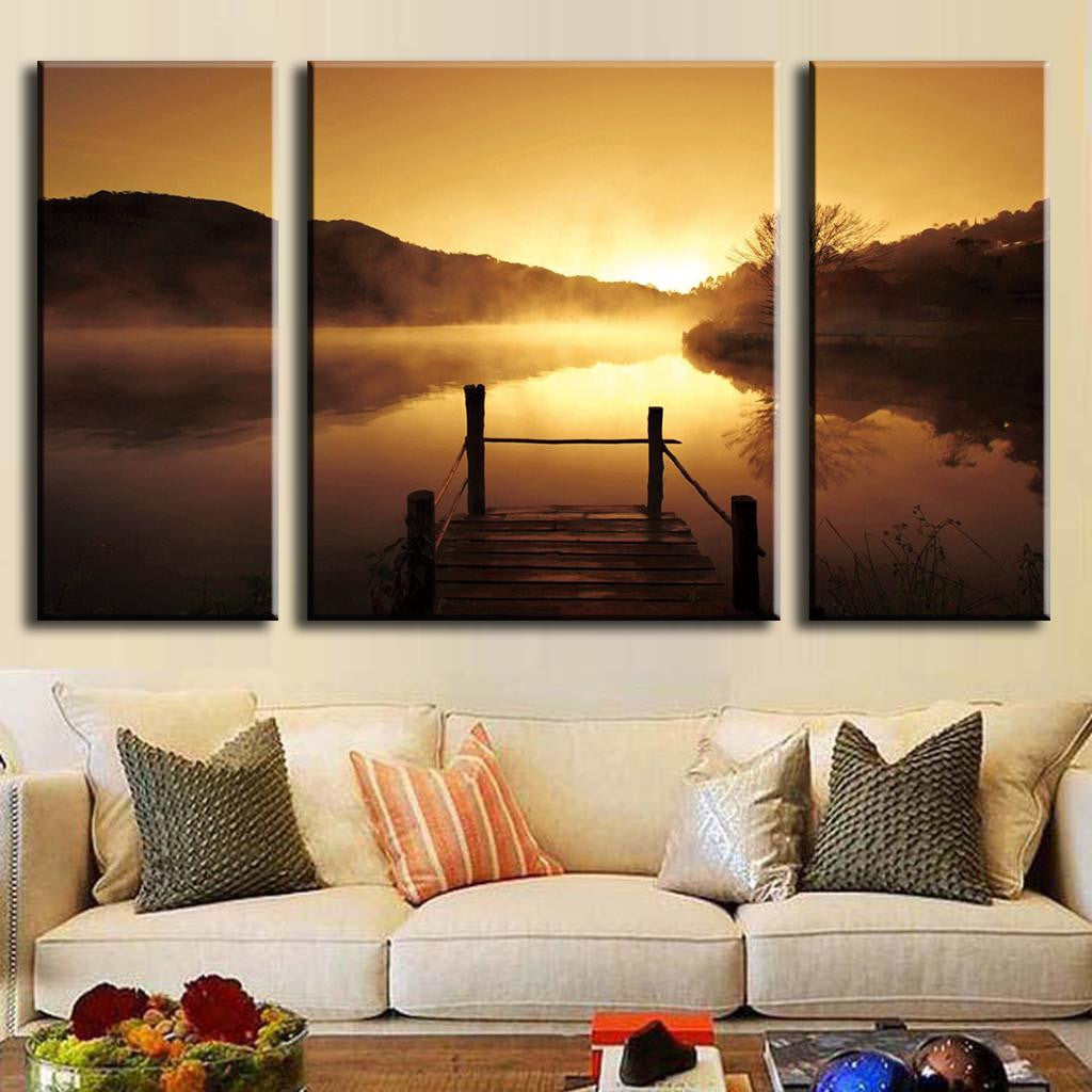 Sunset on the Dock: 3-panel canvas wall art showing tranquil wooden pier overlooking misty lake at sunset, golden sky reflected in calm waters, silhouetted mountains in background, serene landscape photography