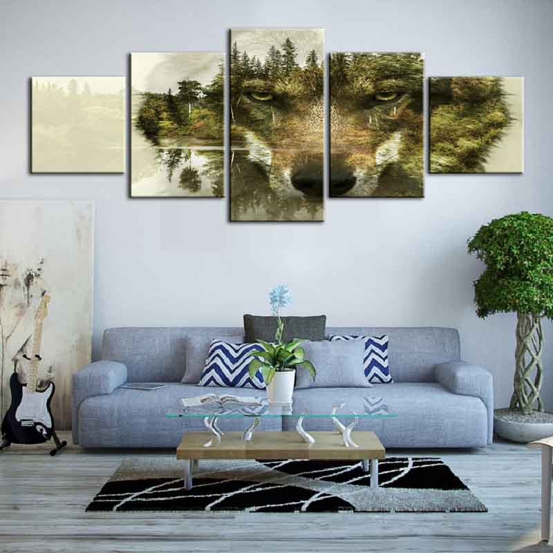 Modern Wolf Face with Nature Background: 5-panel canvas wall art featuring a wolf's face blended with forest scenery, pine trees and misty landscape creating a double exposure effect, displayed above gray couch in living room setting