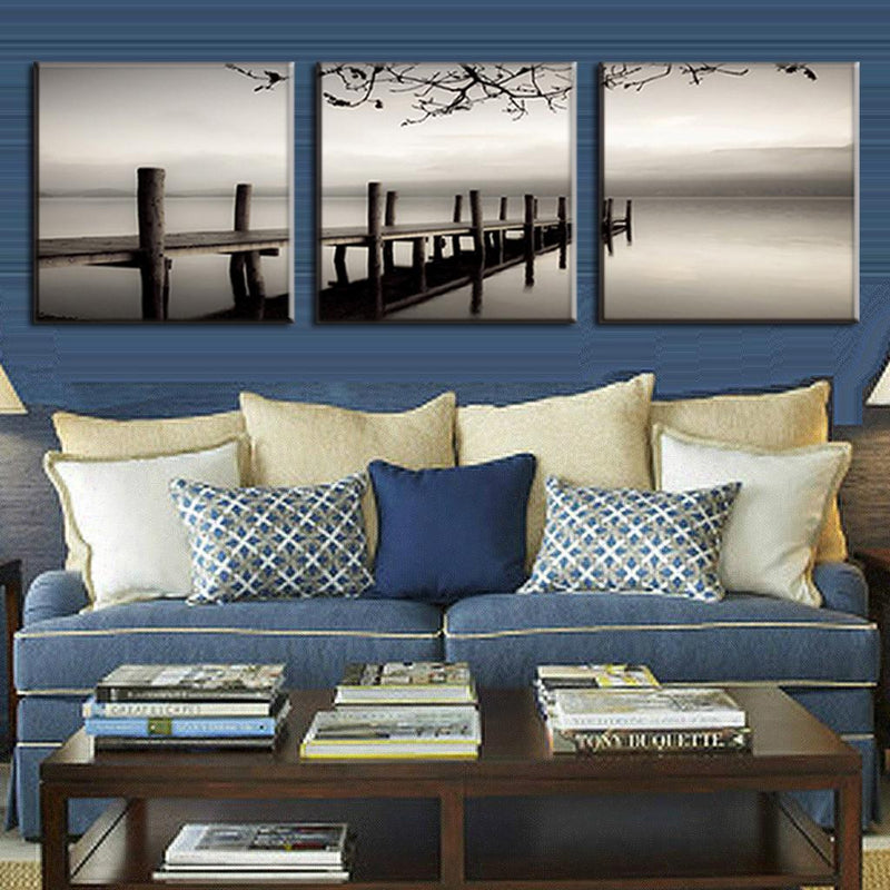Dock and Gray River: Serene black and white triptych canvas wall art featuring a misty wooden pier with weathered posts reflecting on calm water, tree branches silhouetted against a tranquil sky, perfect for coastal home decor