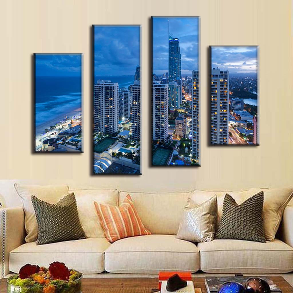Blue Cityscape Beach - 4-panel canvas wall art displaying aerial view of modern coastal city skyline at dusk, featuring illuminated high-rise buildings, oceanfront beach, and dramatic blue twilight sky.