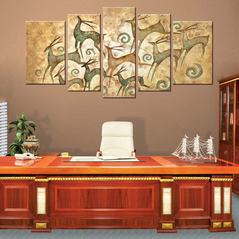 Abstract Elk Print: 5-panel canvas wall art featuring stylized elk silhouettes in teal and green tones against a vintage beige background with decorative swirls, displayed above an office desk creating an elegant wildlife-inspired focal point