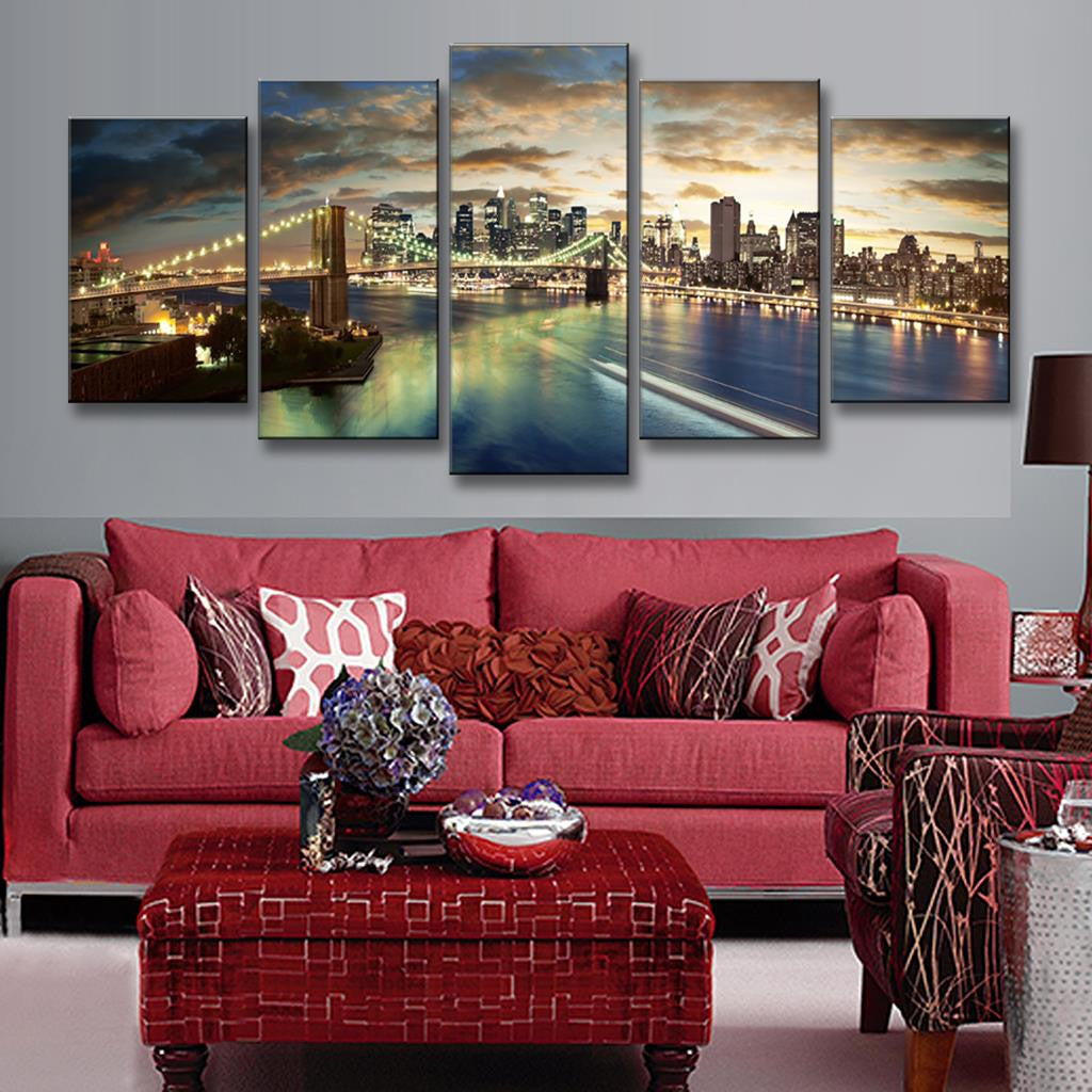 The Brooklyn Bridge Night Scene - Stunning 5-panel canvas wall art featuring illuminated Brooklyn Bridge spanning East River with Manhattan skyline glowing at sunset, reflecting golden lights on tranquil waters against dramatic cloudy sky