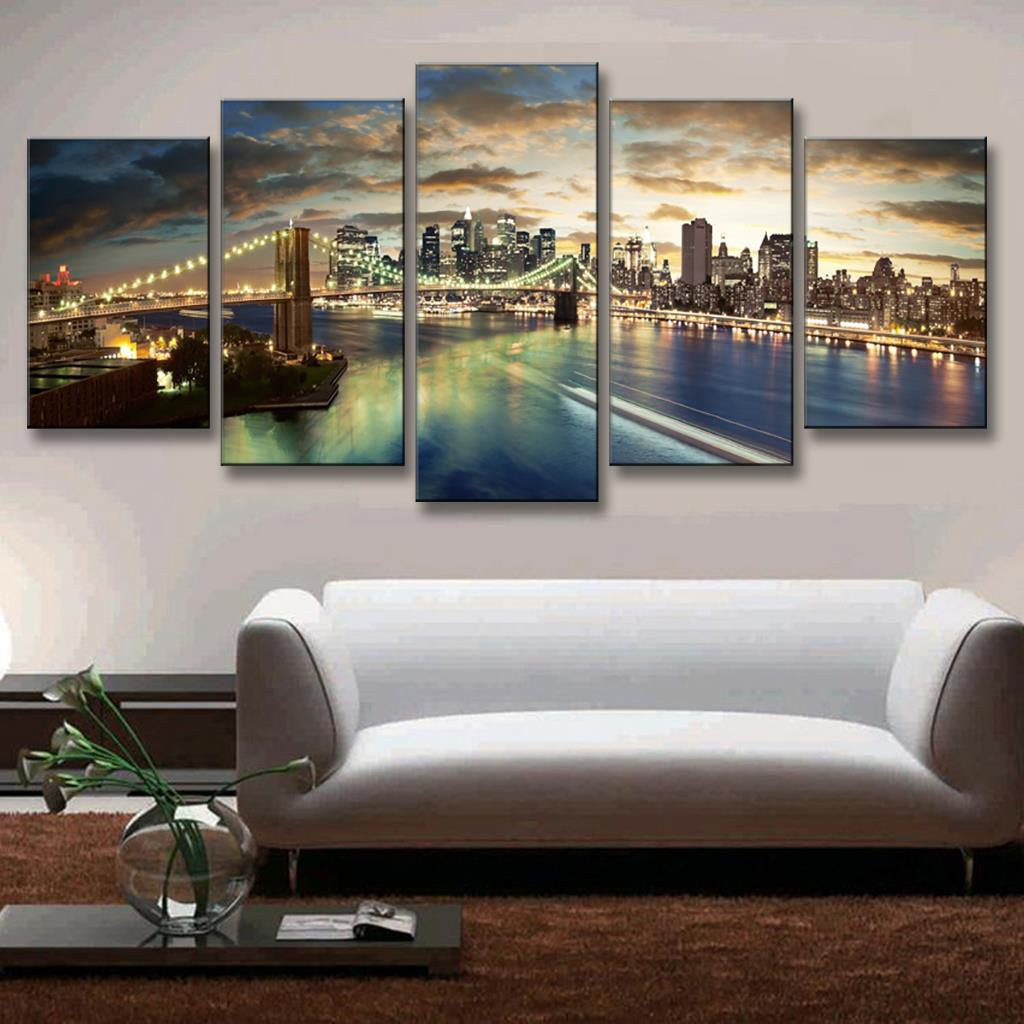 The Brooklyn Bridge Night Scene - Stunning 5-panel canvas wall art featuring illuminated Brooklyn Bridge spanning East River, with NYC skyline glowing against dramatic sunset clouds, reflecting in calm waters below