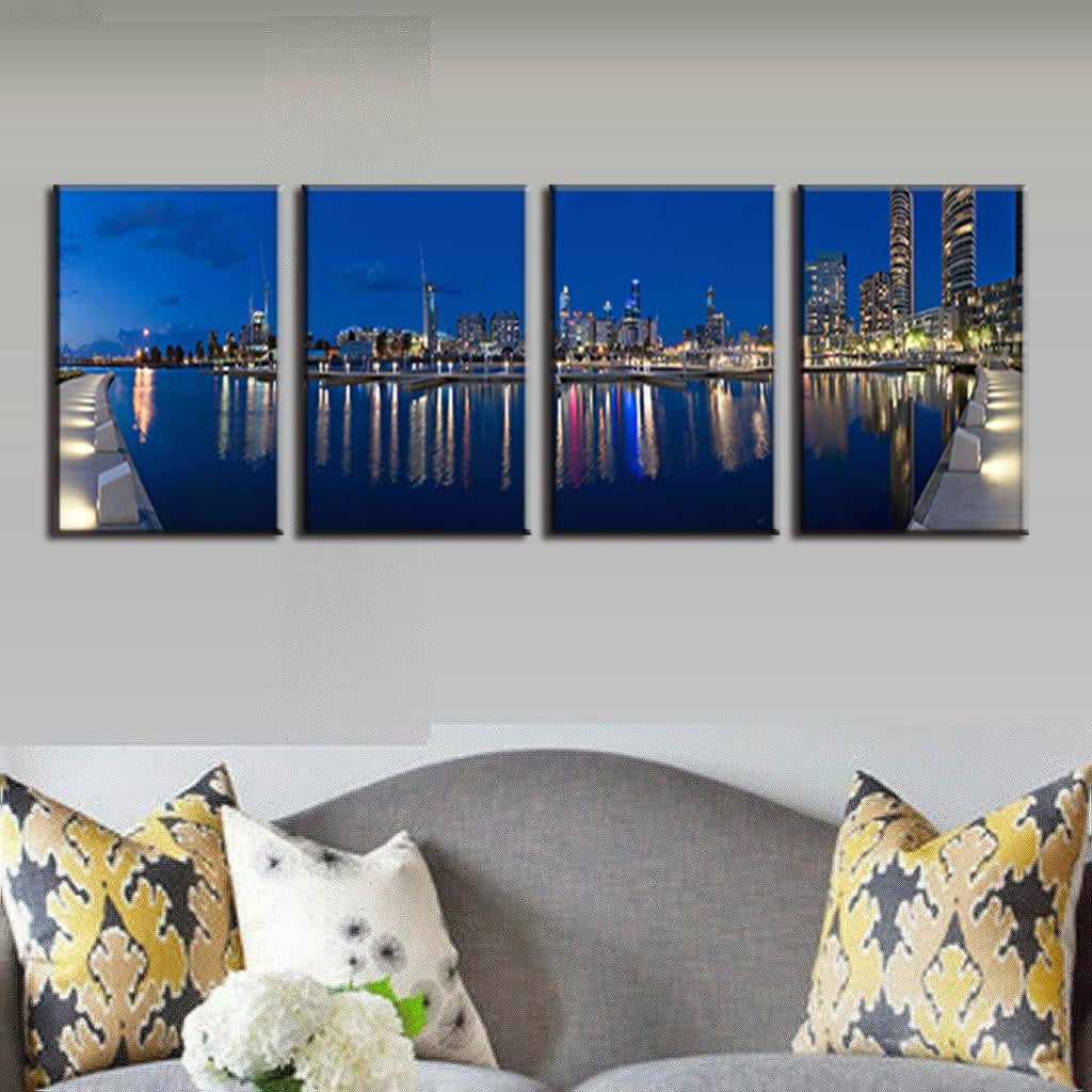 Blue City Night 4-panel canvas wall art showing illuminated cityscape reflected in calm water, with glowing skyscrapers and vibrant city lights creating a stunning panoramic nighttime view of an urban waterfront