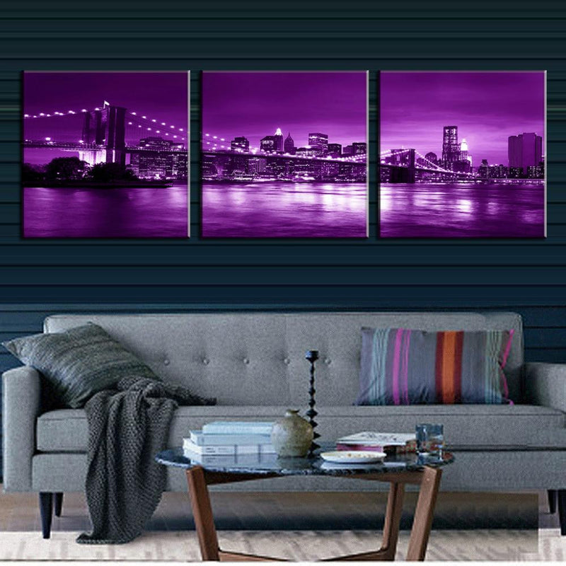 Brooklyn Bridge in Purple Night: Stunning 3-panel canvas wall art featuring iconic bridge and Manhattan skyline reflecting in East River with dramatic purple twilight ambiance and city lights.