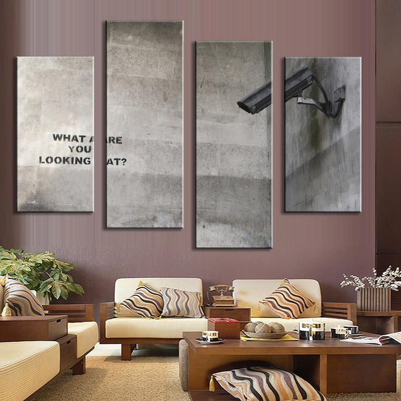 What Are You Looking At Banksy canvas art featuring surveillance camera and graffiti text split across four panels against concrete wall background, modern street art style multi-panel wall decor