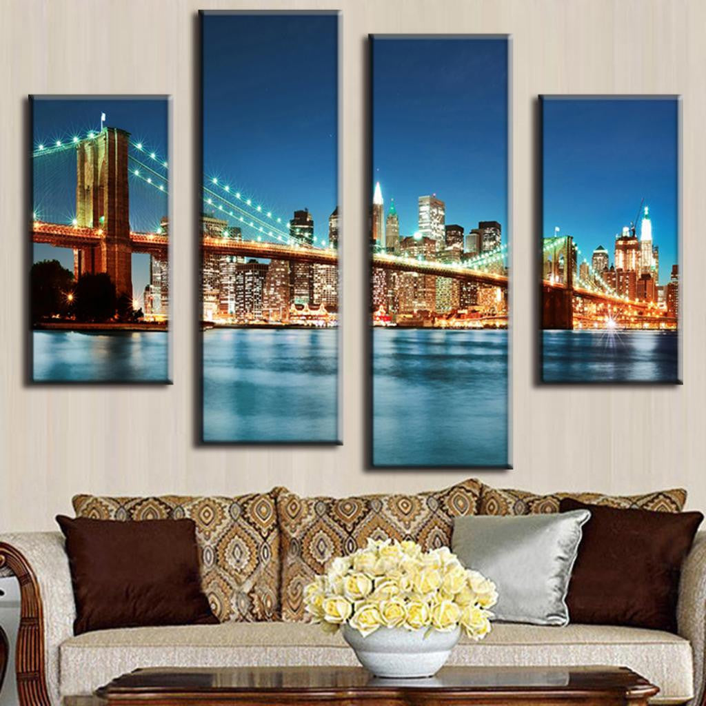 Brooklyn Bridge in Blue Night 4-panel canvas art showing illuminated bridge spanning East River with glowing Manhattan skyline and city lights reflecting on calm waters at dusk