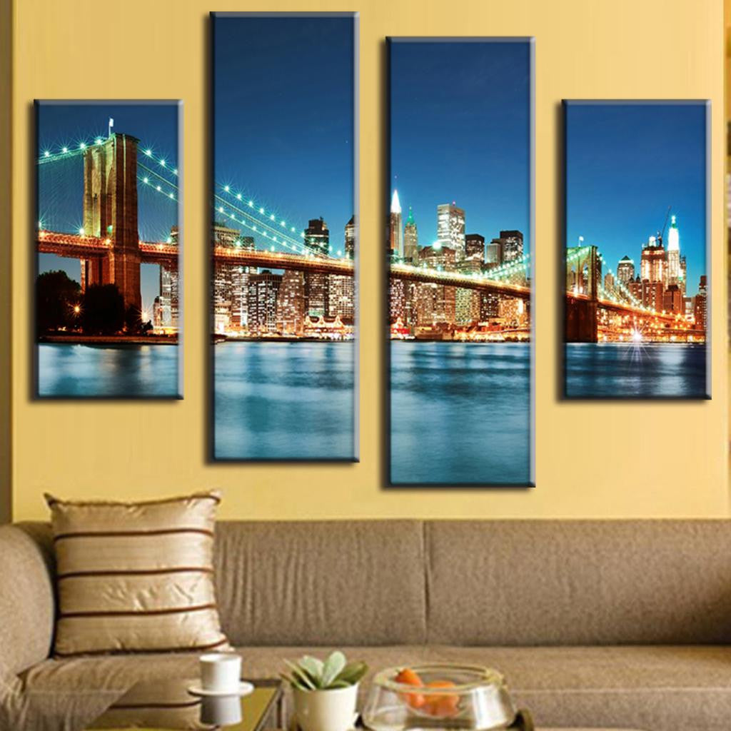 Brooklyn Bridge in Blue Night - 4-panel canvas wall art displaying illuminated NYC skyline with iconic bridge, glowing city lights reflecting on calm water, against deep blue evening sky