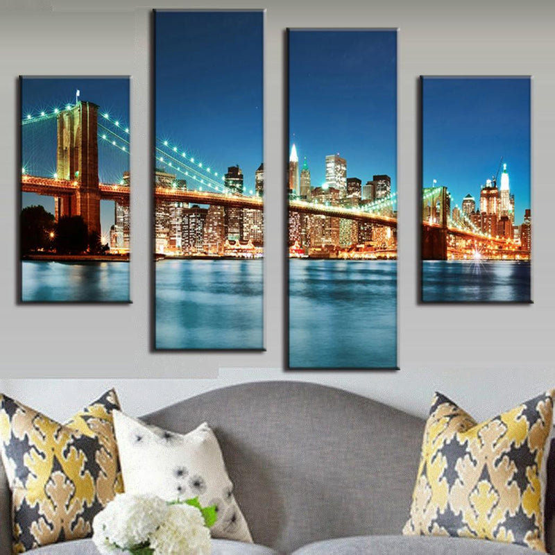 Brooklyn Bridge In Blue Night - 4-piece canvas wall art showing illuminated bridge and Manhattan skyline reflecting on East River at dusk with glowing city lights and turquoise water