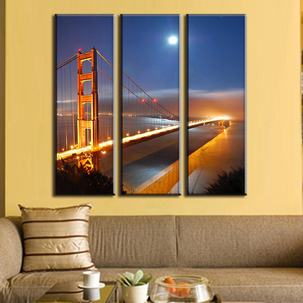 Golden Gate Bridge Under Moonlight - 3-piece canvas wall art showcasing illuminated iconic bridge at night with full moon, glowing orange lights reflecting on San Francisco Bay, vibrant twilight sky creating dramatic cityscape view
