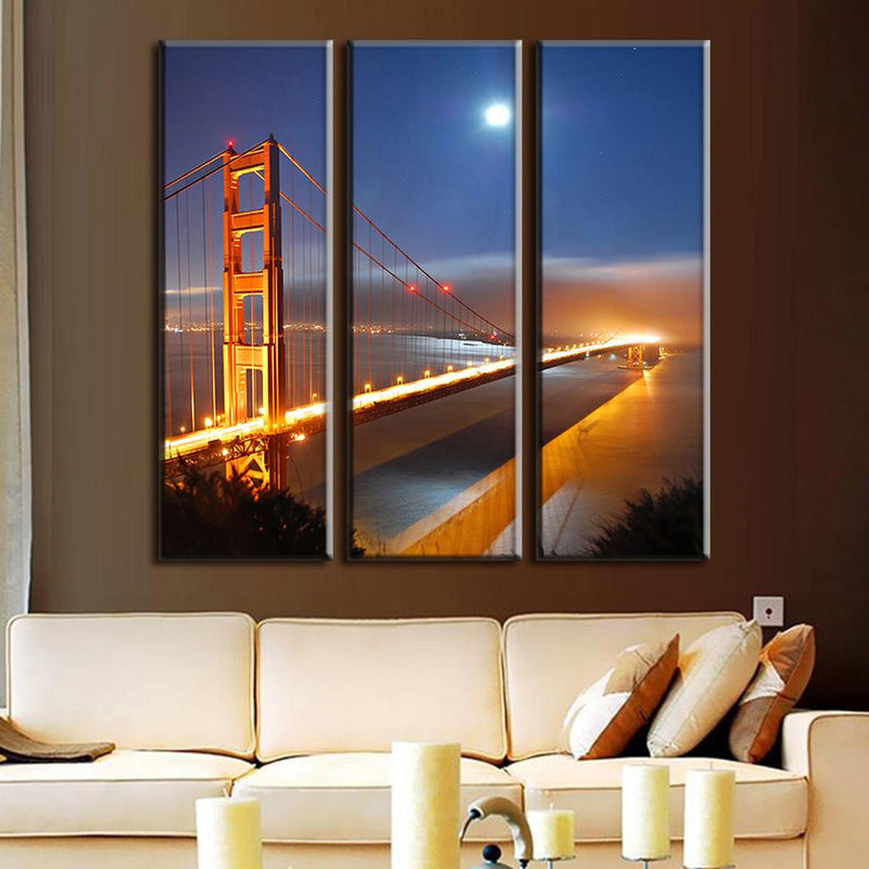 Golden Gate Bridge Under Moonlight - 3-piece canvas wall art showing illuminated bridge at night with full moon, city lights reflecting on water, orange bridge towers against deep blue sky creating dramatic night scene in San Francisco