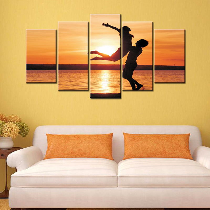 Uplifted Silhouettes 5-panel canvas wall art featuring silhouetted figures against vibrant orange sunset over water, creating romantic and joyful scene with warm tones perfect for home decor